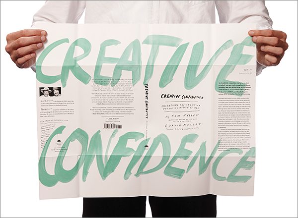 A person holding up a magazine with the words creative and confidence written on it.