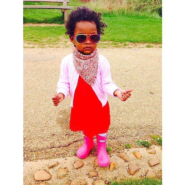 A little girl wearing pink boots and sunglasses.